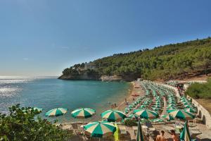 ein Strand mit vielen Sonnenschirmen und Menschen darauf in der Unterkunft Hotel degli Ulivi in Vieste