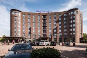 ein großes Backsteingebäude mit Autos auf einem Parkplatz in der Unterkunft Mercure Hotel Hamburg City in Hamburg