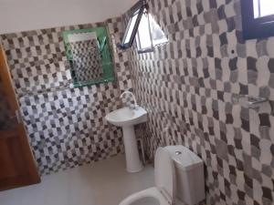 a bathroom with a white toilet and a sink at Belle Villa Nassima in Thiès +30 photos
