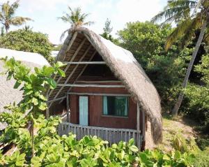 a small house with a thatched roof at Anastasea, Palm Tree Garden Lodging in Praia do Tofo