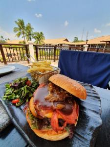 a sandwich on a table with a basket of french fries at Mayang Sari Beach Resort in Lagoi
