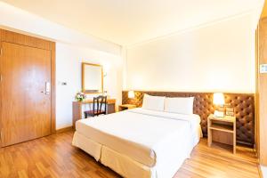 - une chambre avec un grand lit blanc et un bureau dans l'établissement Viva Hotel Songkhla, à Songkhla
