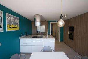 a kitchen with white cabinets and a blue wall at DUPLEX DE CARA EL MAR 210 m2 in Tamariu