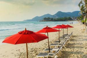 a row of red umbrellas and chairs on a beach at Kirikayan Boutique Resort - SHA Extra Plus in Chaweng