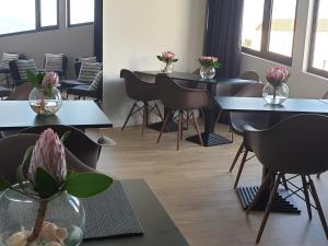 ein Zimmer mit Tischen, Stühlen und Blumenvasen in der Unterkunft Porto Velho Boutique Hostel in Madalena