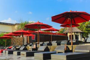 - un ensemble de chaises avec des parasols rouges sur la terrasse dans l'établissement Kirikayan Boutique Resort - SHA Extra Plus, à Chaweng