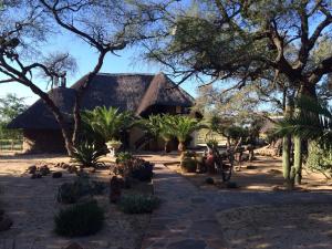 a house with a thatched roof and some trees at Roidina Safari Lodge in Omaruru