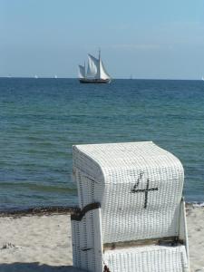 a sail boat in the ocean with a white beach chair at Landurlaub Regenholz in Kronsgaard