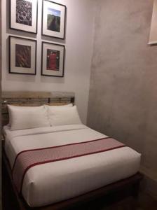 a bed in a room with pictures on the wall at The Bricks Hotel in Dumaguete