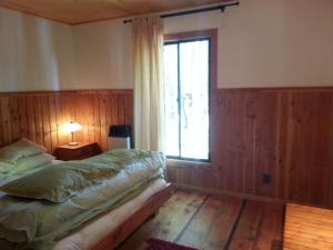 Un dormitorio con una cama y una ventana en Cabaa Oregn con hot tub exclusivo cerca de termas y lago, en Coñaripe