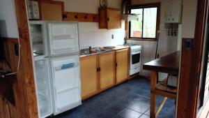 Una cocina con un refrigerador blanco y una estufa. en Cabaa Oregn con hot tub exclusivo cerca de termas y lago, en Coñaripe