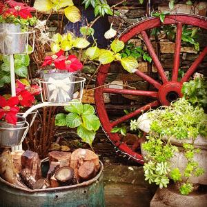 un giardino con carro rosso, piante e fiori di Feggaropetra Inn Magic Mountain House a Palaios Panteleimon