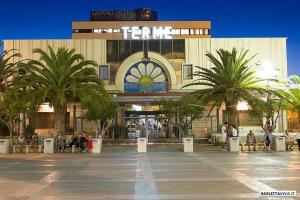 un centro comercial con palmeras frente a un edificio en CENTRALISSIMO MINI APPARTAMENTO 1° piano en Margherita di Savoia