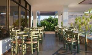 a restaurant with wooden tables and chairs and windows at Anavadia Hotel-All Inclusive in Kolymbia