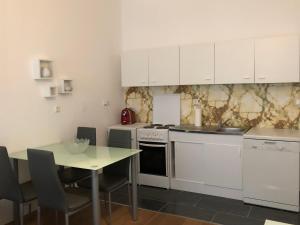 uma cozinha com armários brancos e uma mesa com cadeiras em Green apartment em Viena