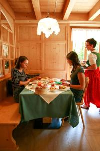 Agritur Dal Fior La Casa nel Bosco في Roncegno: مجموعة من النساء يجلسون حول طاولة مع كعكة