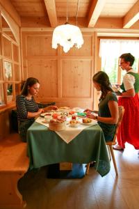 Un gruppo di donne sedute intorno a un tavolo con una torta di Agritur Dal Fior La Casa nel Bosco a Roncegno