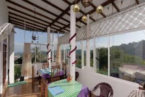 a room with a table and chairs and windows at Kandyan White Holiday Homes in Kandy