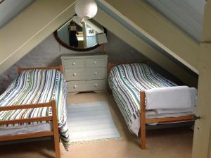 - une chambre mansardée avec 2 lits et un miroir dans l'établissement Potato, Barafundle Barns, SA71 5LS, à Pembroke