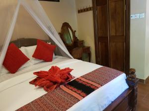 a bed with a red flower on top of it at Ombak Dive Resort Perhentian Island in Perhentian Islands