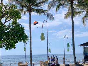 a kite flying over the beach with palm trees at Villa Cahaya - Bali Sea Villas Beachfront and private pool in Pengastulan