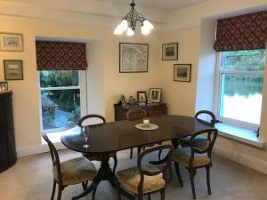 una sala da pranzo con tavolo e sedie e due finestre di Riverbank House Bed and Breakfast Innishannon a Inishannon