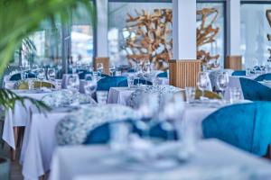 Calanova Sports Residence في بالما دي ميورقة: غرفة طعام مع طاولات بيضاء وكراسي زرقاء