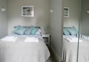 a bedroom with two beds with blue pillows and a mirror at Harlow apartment in Harrogate