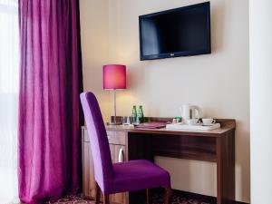 Camera d'albergo con scrivania e sedia viola di Hotel Woiński Spa a Lubniewice