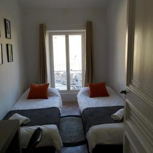 two beds in a room with a window at Suite Familiale Saint-Exupéry-Spacieux-Hypercentre-wifi-vélo in Castelnaudary