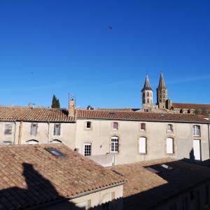 un edificio con una torre sobre los tejados en Suite Familiale Saint-Exupéry-Spacieux-Hypercentre-wifi-vélo en Castelnaudary