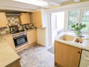 a kitchen with a sink and a stove top oven at 2 Rose Cottages in Looe