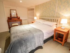 a bedroom with a bed and a table with a mirror at 2 Rose Cottages in Looe