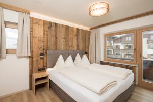 Un dormitorio con una gran cama blanca y una ventana en Angerer Alpine Suiten und Familienappartements Tirol, en Reith im Alpbachtal