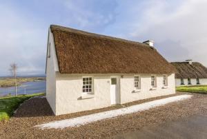 een oud wit gebouw met een bruin dak bij Fern Cottage in Killinaboy