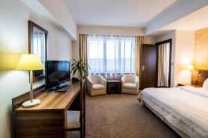 a hotel room with a bed and a desk with a television at Grand Hotel in Târgu-Mureş