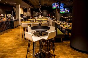 a restaurant with a table and chairs and a bar at H4 Hotel Mönchengladbach im BORUSSIA-PARK in Mönchengladbach