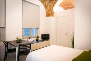 a bedroom with a bed and a desk with a television at Mameli Comfort in Casale Monferrato
