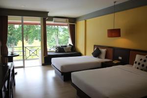 a hotel room with two beds and a balcony at Aekpailin River Kwai Resort in Kanchanaburi City