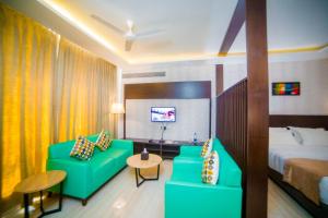 a hotel room with a green couch and a bed at Fortune Plaza Hotel in Udupi