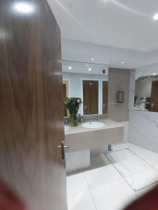 a bathroom with a sink and a mirror and a door at Eagle Hotel Luton Airport in Luton