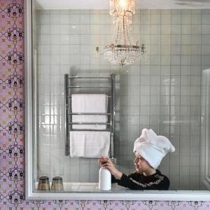 Uma mulher com um chapéu de chefe sentada no lavatório da casa de banho. em Huskvarna Stadshotell em Huskvarna