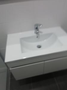 lavabo blanco con grifo de plata en Hospedaria Nunes Pinto, en Termas de Sao Pedro do Sul