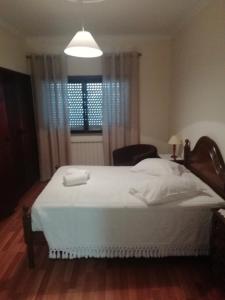 een slaapkamer met een groot wit bed en een raam bij Hospedaria Nunes Pinto in Termas de Sao Pedro do Sul