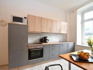 una cocina con electrodomésticos de acero inoxidable y una mesa con fruta en Apartment in a villa with garden in Borstendorf en Wünschendorf