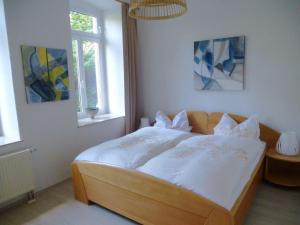 a bedroom with a large bed with white sheets and pillows at Apartment in a villa with garden in Borstendorf in Wünschendorf