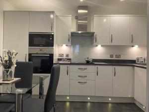 a kitchen with white cabinets and a table with chairs at 23 Hedgefield House in Inverness