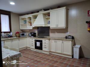 cocina con armarios blancos y fogones en Casa Rural Aguas del Venero, en Losar de la Vera