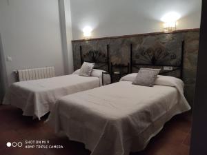 2 camas con sábanas blancas en una habitación en Casa Rural Aguas del Venero, en Losar de la Vera