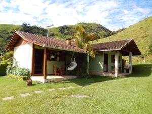 una pequeña casa verde y blanca con una colina en Pousada do Sonho, en Visconde De Maua
